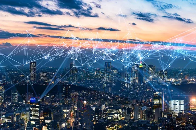 A vibrant cityscape at dusk with interconnected digital lines overlaying skyscrapers, symbolizing connectivity and technological advancement.